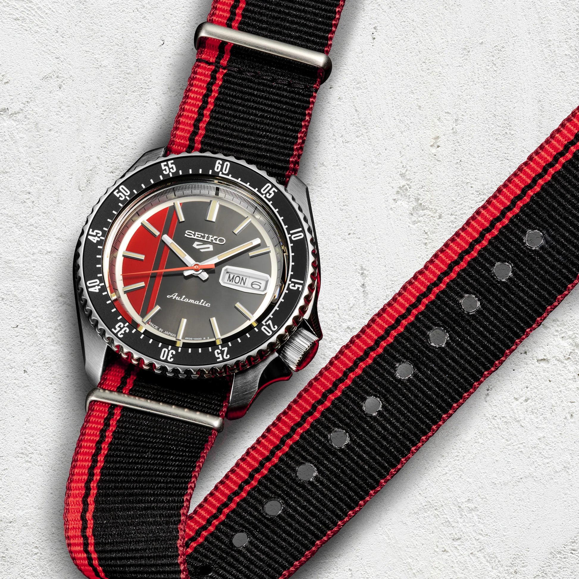 SEIKO SRPK71 U.S. Special Creation – black and red striped dial and nylon strap, inspired by vintage race cars, with a rotating bezel, automatic movement, and 100m water resistance.