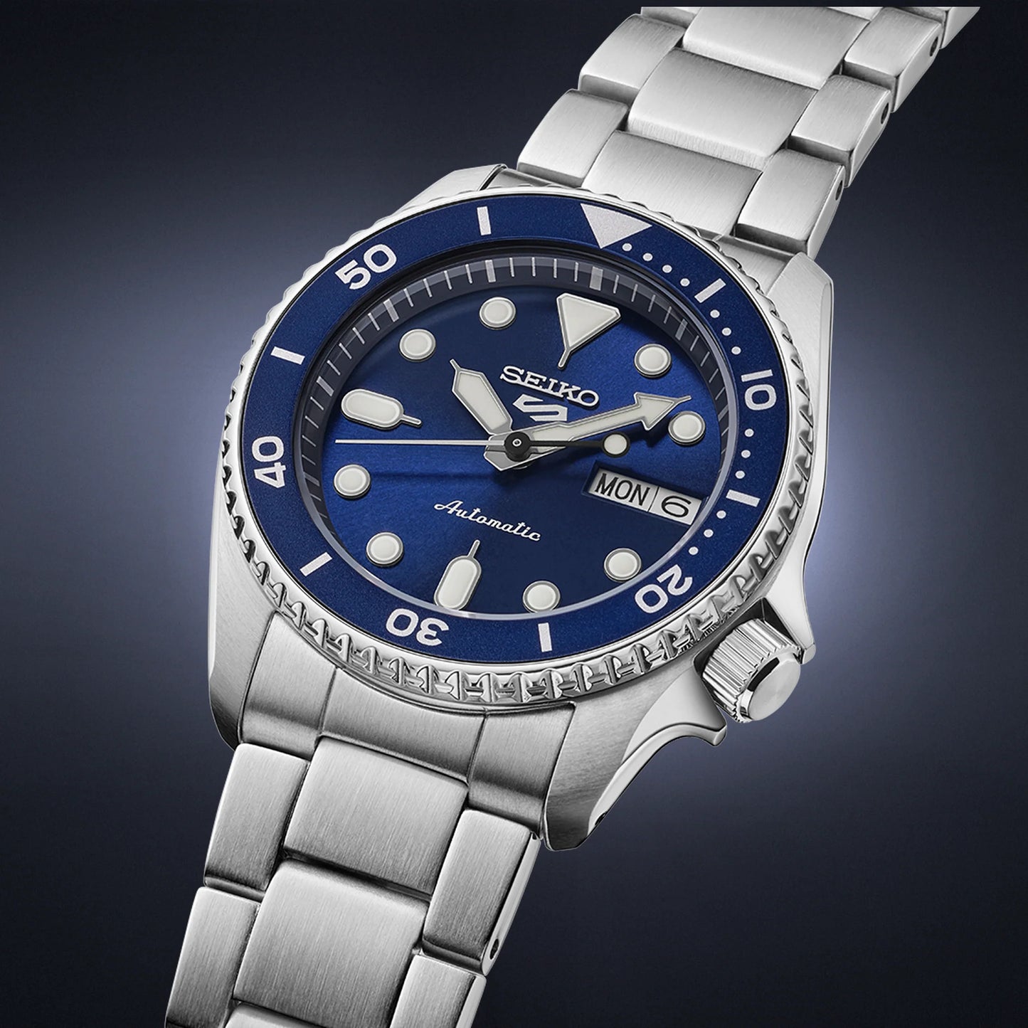 Seiko watch with blue dial and silver metal strap on a dark background