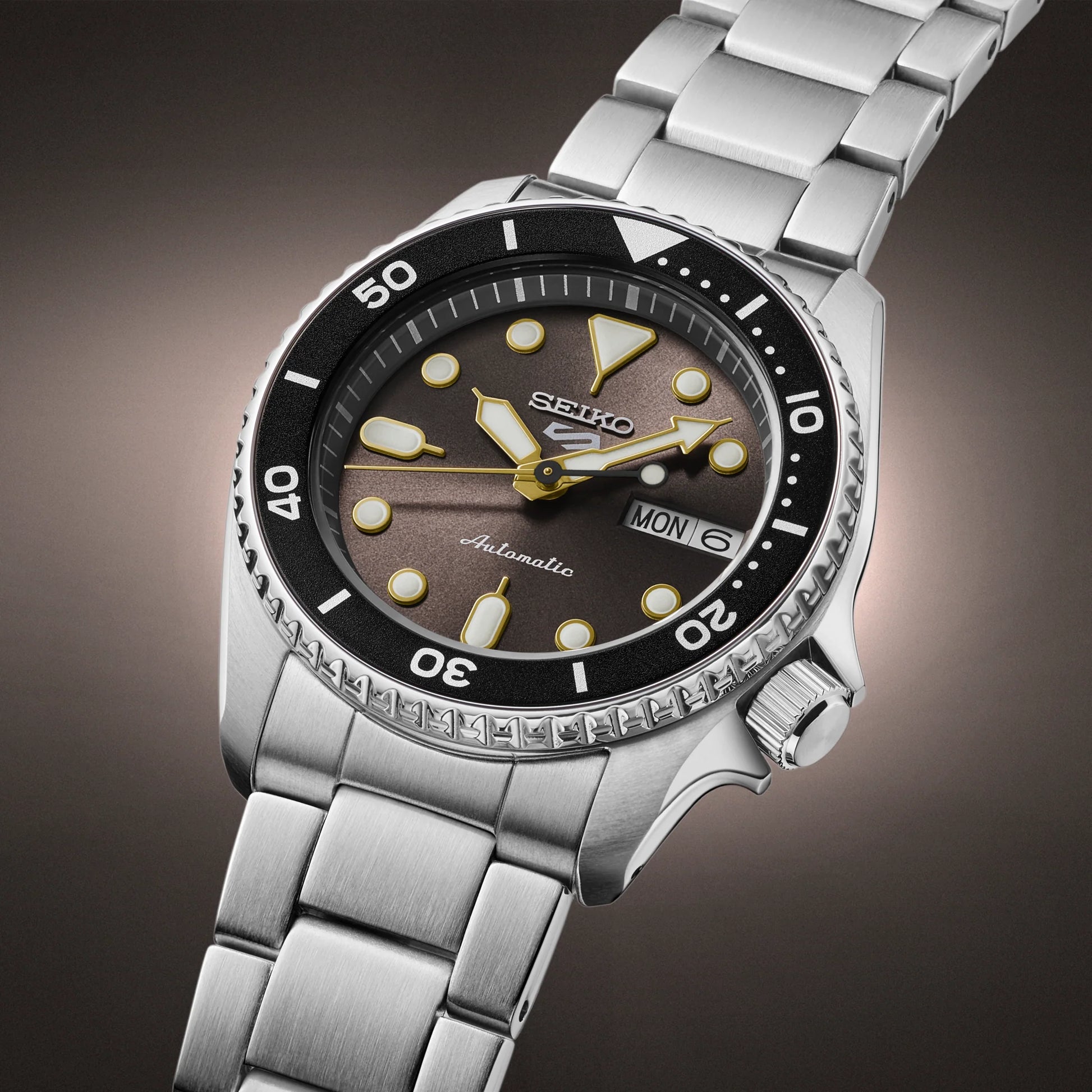 Silver Seiko watch with a dark brown dial on a gradient background
