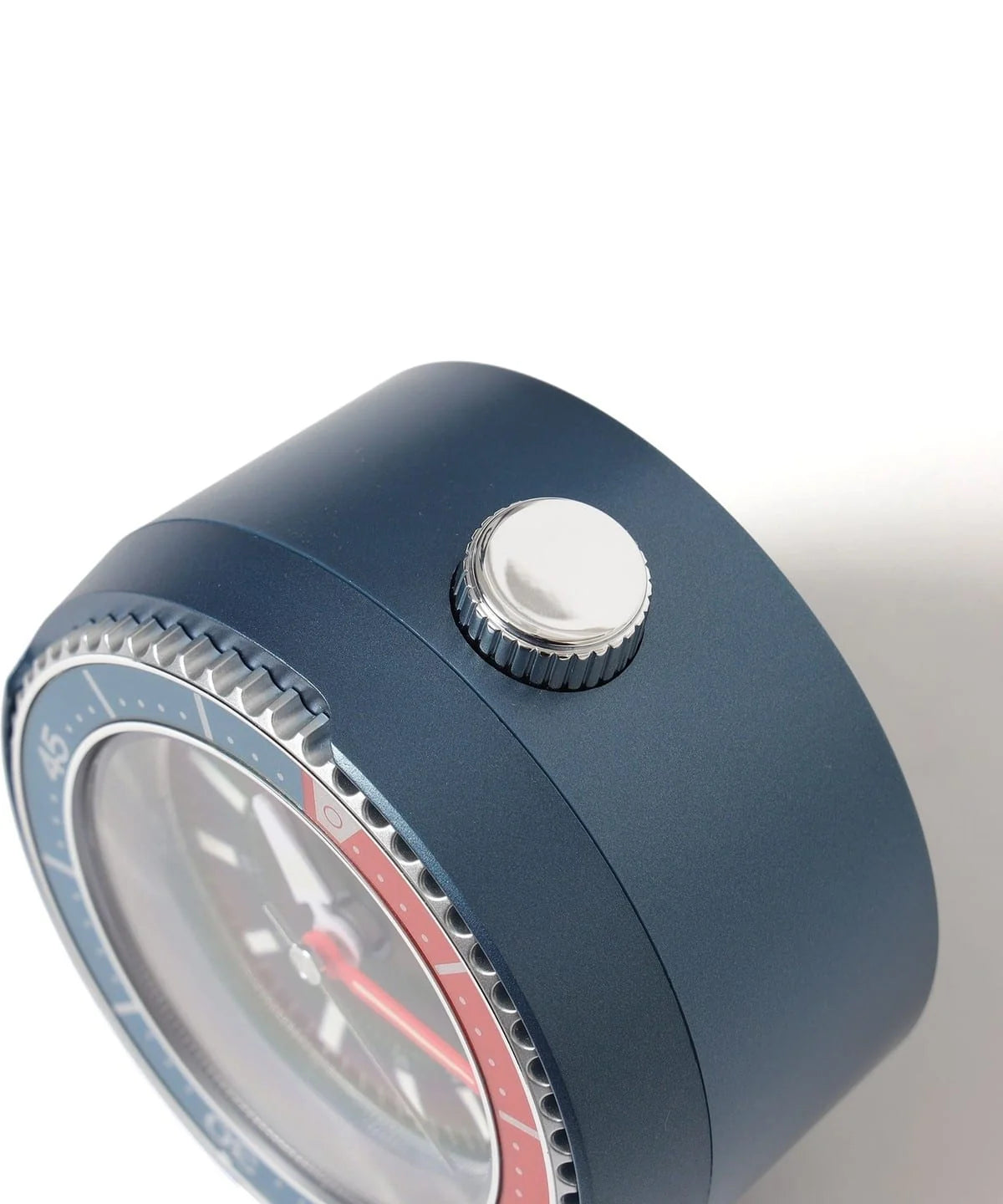 Close-up side view of SEIKO QHE207LLH alarm clock showing the blue metallic-finish case, silver top button, and red-blue rotating bezel.