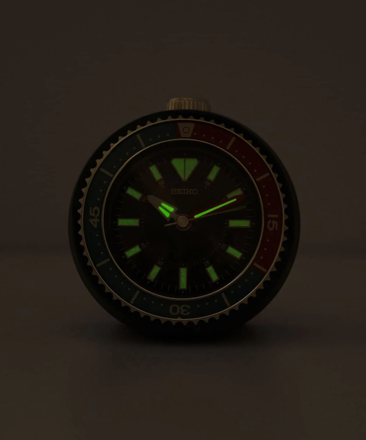 SEIKO QHE207LLH alarm clock in the dark with glowing LumiBrite hands and hour markers for nighttime readability.
