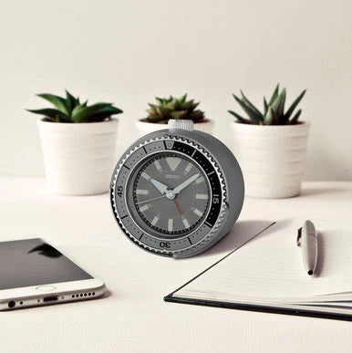 SEIKO QHE207NLH rotating bezel desk alarm clock displayed on a modern workspace with plants, notebook, pen, and smartphone.
