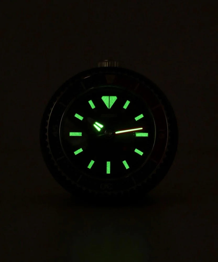 SEIKO QHE207KLH rotating bezel desk alarm clock displayed on a workspace with small plants, notebook, pen, and smartphone.