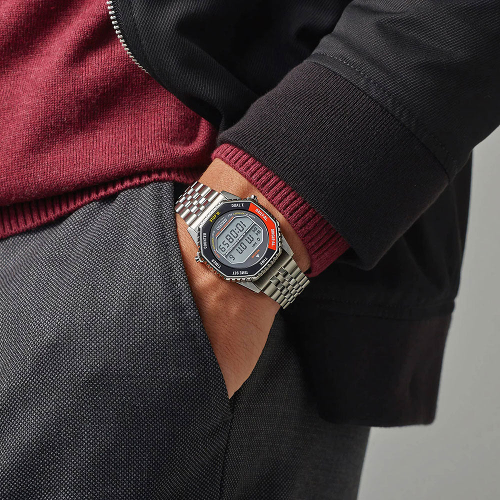 Person wearing a digital watch with a maroon sleeve and gray jacket on a neutral background