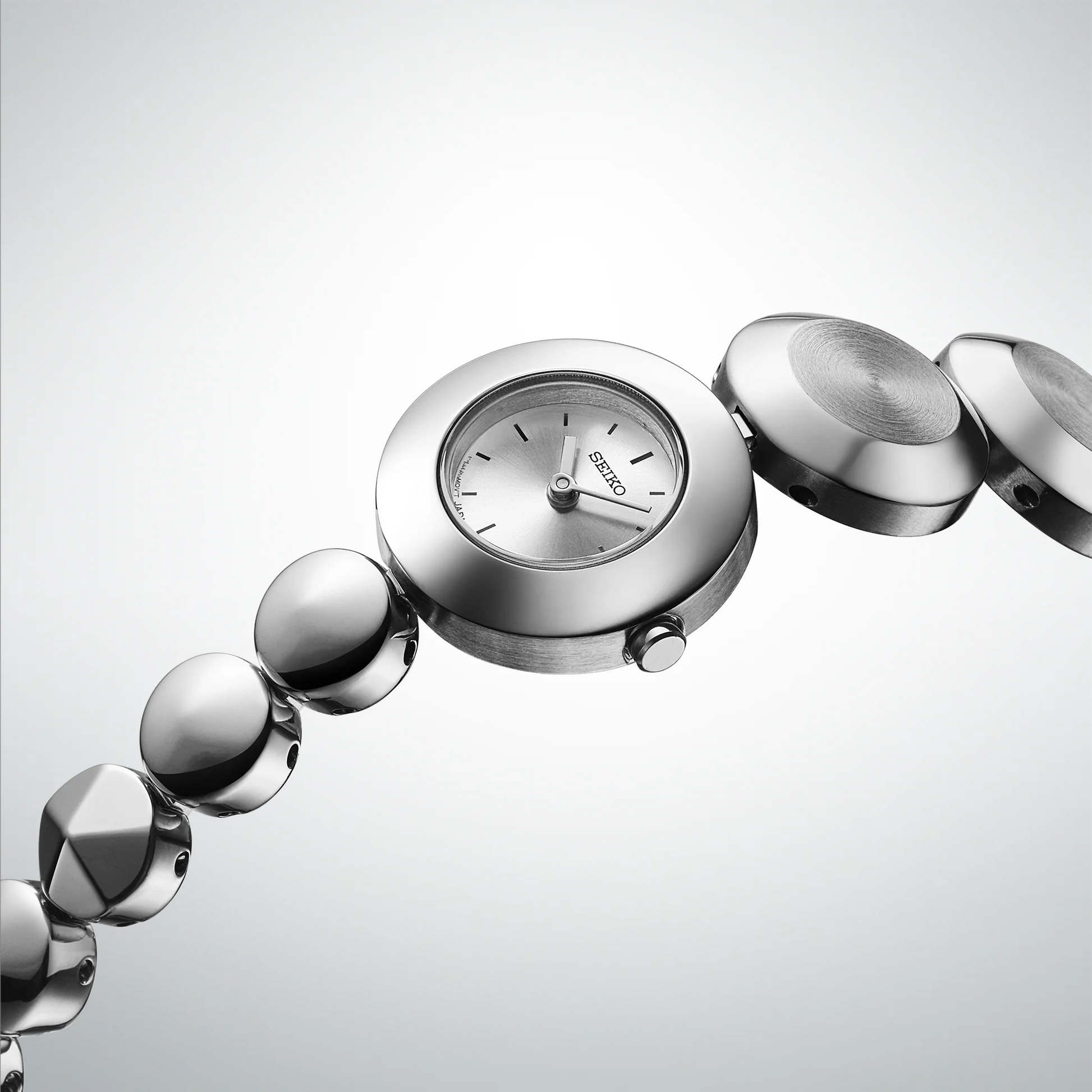 Silver bracelet watch with a white face on a light gray background