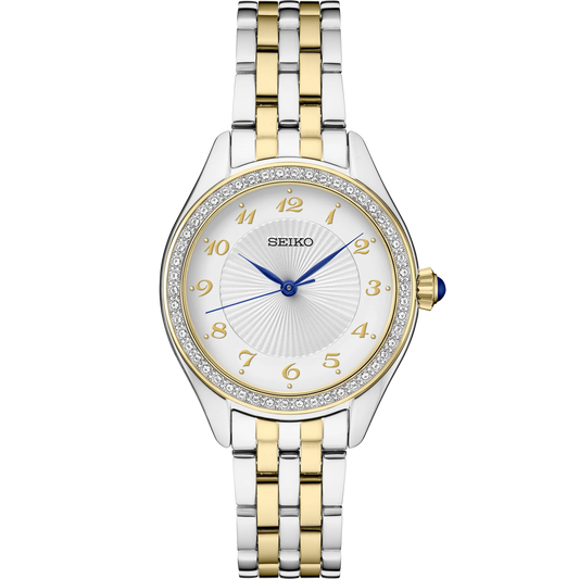 Seiko Essentials SUR392 quartz watch with patterned white dial, crystal accents, gold-tone Arabic numerals, blue hands, blue cabochon crown, two-tone stainless steel case and bracelet, and curved Hardlex crystal.