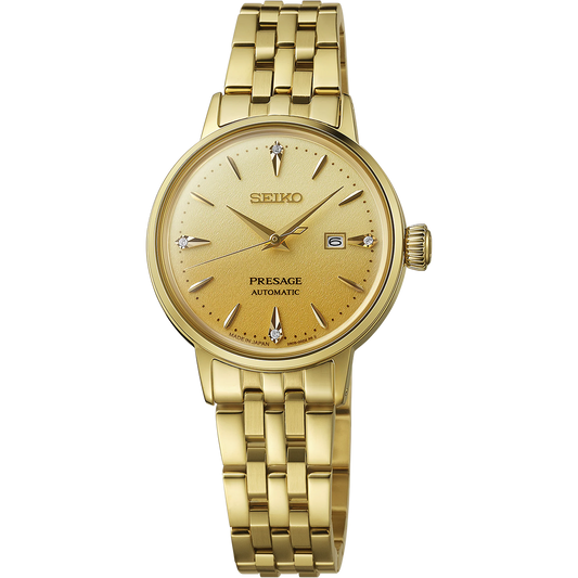 Seiko Presage Cocktail Time SRE018 women’s automatic watch inspired by the Eggnog cocktail. Features a 30.1 mm stainless steel case with gold finish, golden pressed-pattern dial with four diamond hour markers, gold-tone hands, and a five-row gold bracelet. Powered by Caliber 2R05 automatic movement with 21 jewels, 40-hour power reserve, and manual winding. Includes box-shaped Hardlex crystal, date display at 3 o’clock, and 50-meter water resistance