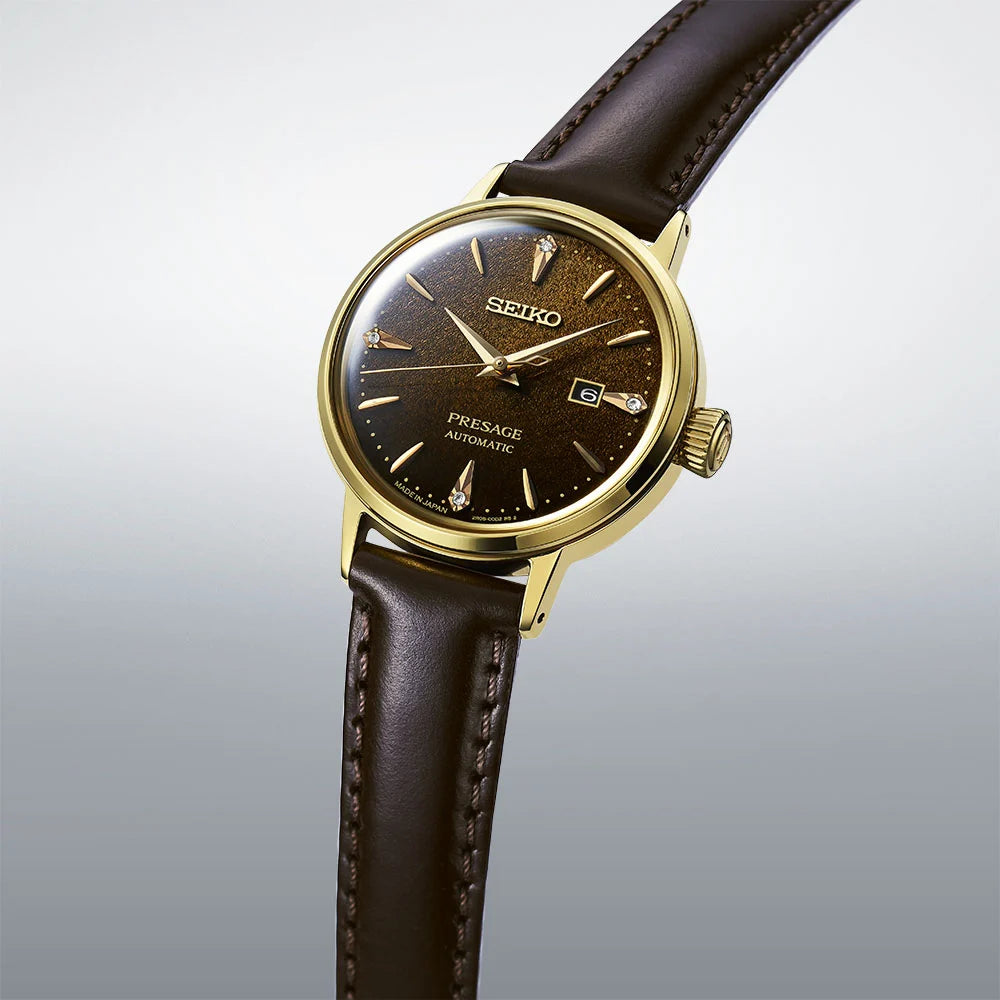 Seiko watch with brown leather strap and gold casing on a light gray background