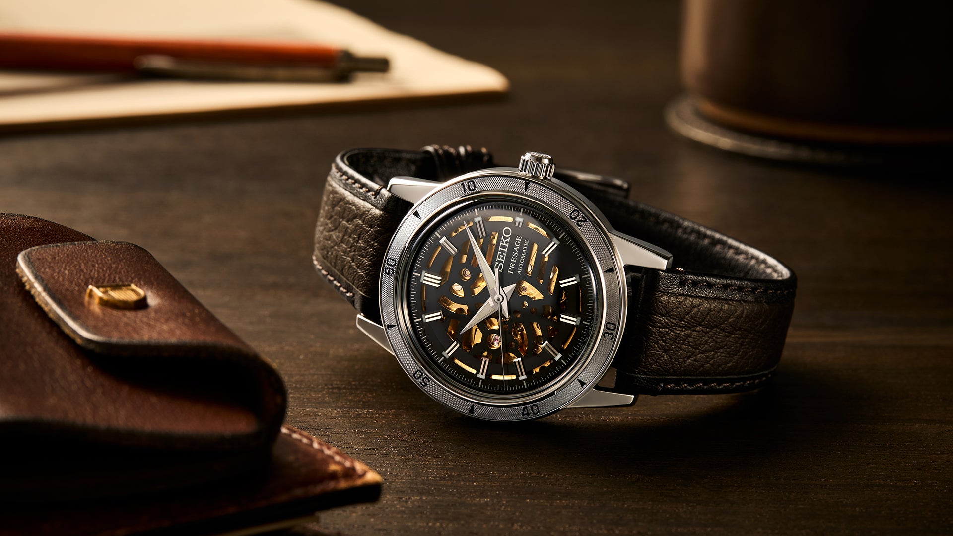 Luxury watch with black leather strap on a dark surface