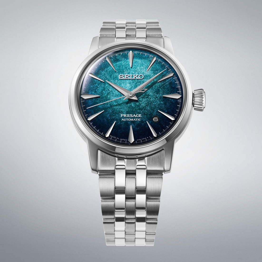 A Seiko Pressage Automatic watch with a silver stainless steel case and link bracelet, featuring a textured blue and teal dial.