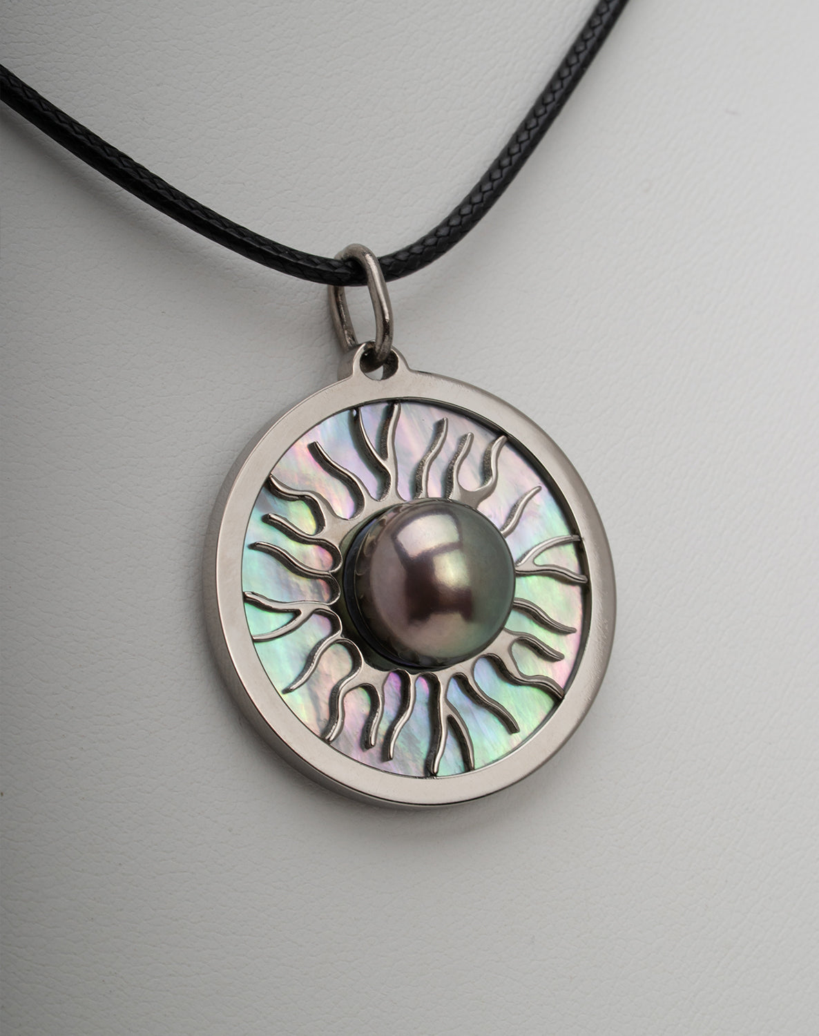 Titanium black freshwater pearl necklace with mother-of-pearl inlay, 10-11mm dyed black button-shaped pearl, exclusive sun-inspired design by Miseki Jewelry, adjustable waxed cotton cord, stainless steel lobster clasp