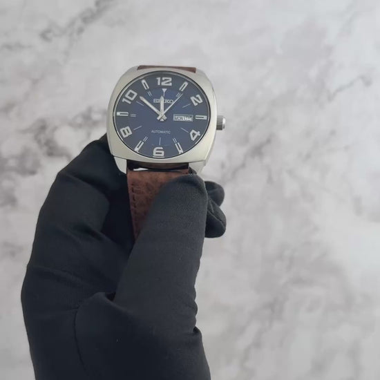Seiko SNKN37 Recraft – bold blue dial automatic watch with retro cushion-shaped case, brown leather strap, luminous markers, see-through caseback, and 41-hour power reserve.