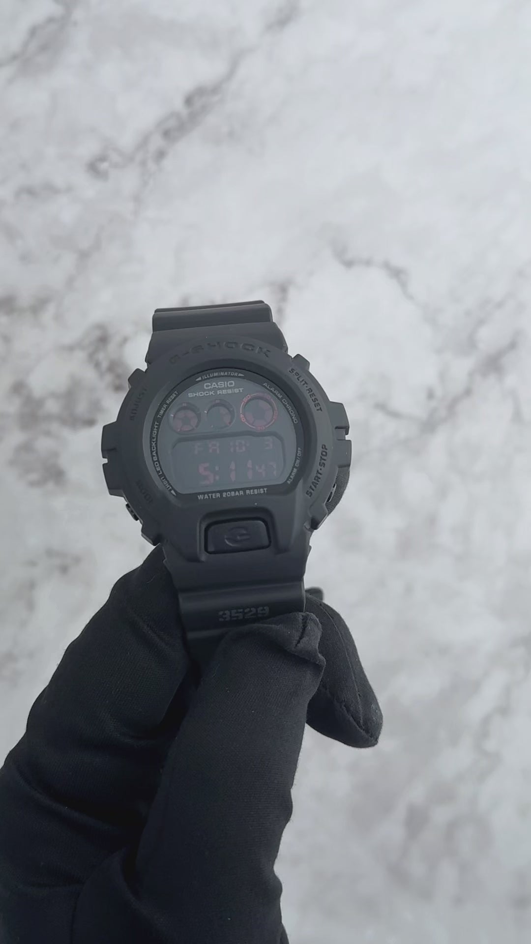 Casio G-SHOCK DW6900MS-1 digital watch in stealth matte black resin case and band with red accents and black ion-plated buttons. Features shock resistance, mineral glass, 200-meter water resistance, electro-luminescent blue-green backlight with afterglow, stopwatch, countdown timer, multi-function alarm, hourly time signal, flash alert, full auto-calendar, and 12/24-hour format. Case size 53.2 × 50 × 18.7 mm, weight 67 g, powered by CR2016 battery with approx. 2-year life.”