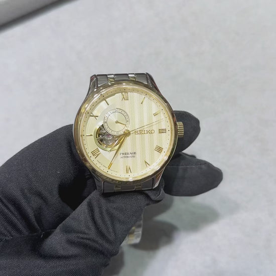 Seiko Presage SSA464 Japanese Garden automatic watch with ivory-gold textured dial, Roman numeral markers, open-heart display, gold-tone bezel, and two-tone stainless steel bracelet.