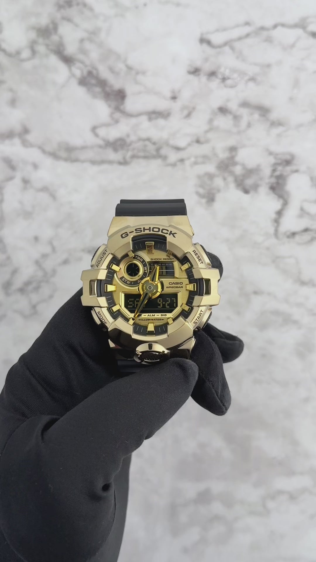 A Casio G-Shock GM700G-9A watch with a black band and gold ion-plated stainless steel bezel, featuring an analog-digital display.