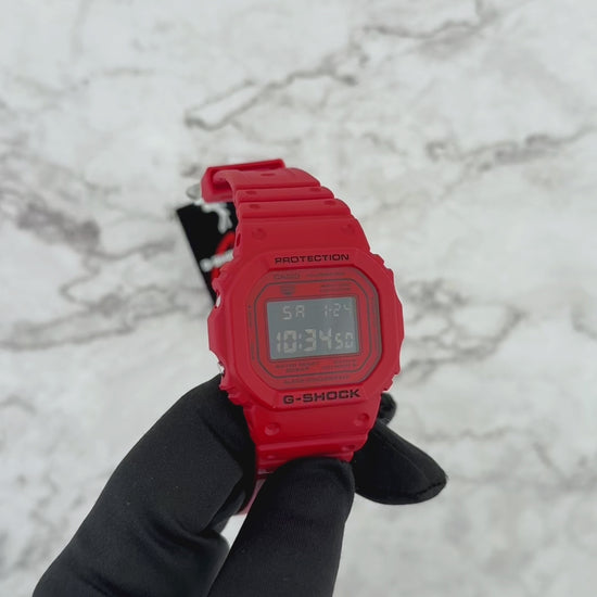 Casio G-SHOCK DW5600RRB-4 digital watch with a bold red resin case and band, black inverted LCD display, classic square 5600 design, shock-resistant construction, and 200-meter water resistance.