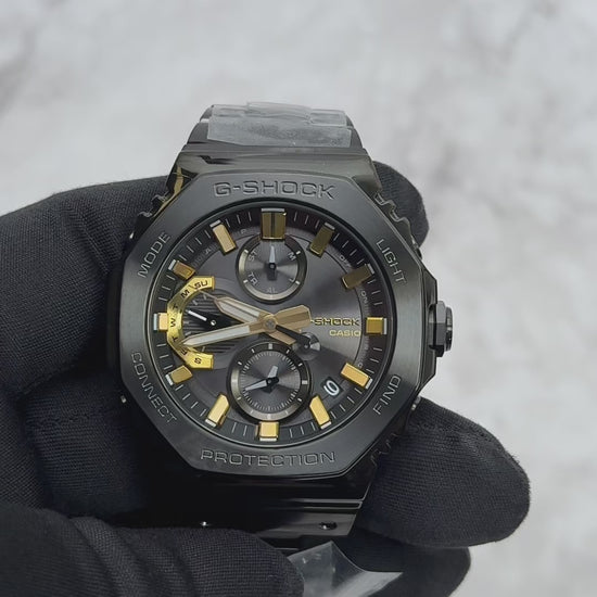 Casio G-SHOCK GMCB2100ZE1A 50th Anniversary full-metal black ion-plated watch with gold accent and binary code dial, limited edition released April 2025
