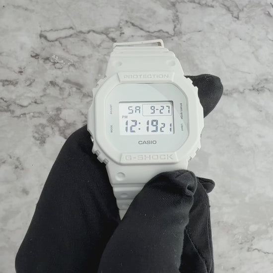 Casio G-SHOCK DW5600WW-7 all-white square model with resin case, bezel, band, and glass in monochrome design, featuring shock resistance, 200M water resistance, LED Super Illuminator backlight, stopwatch, and countdown timer.