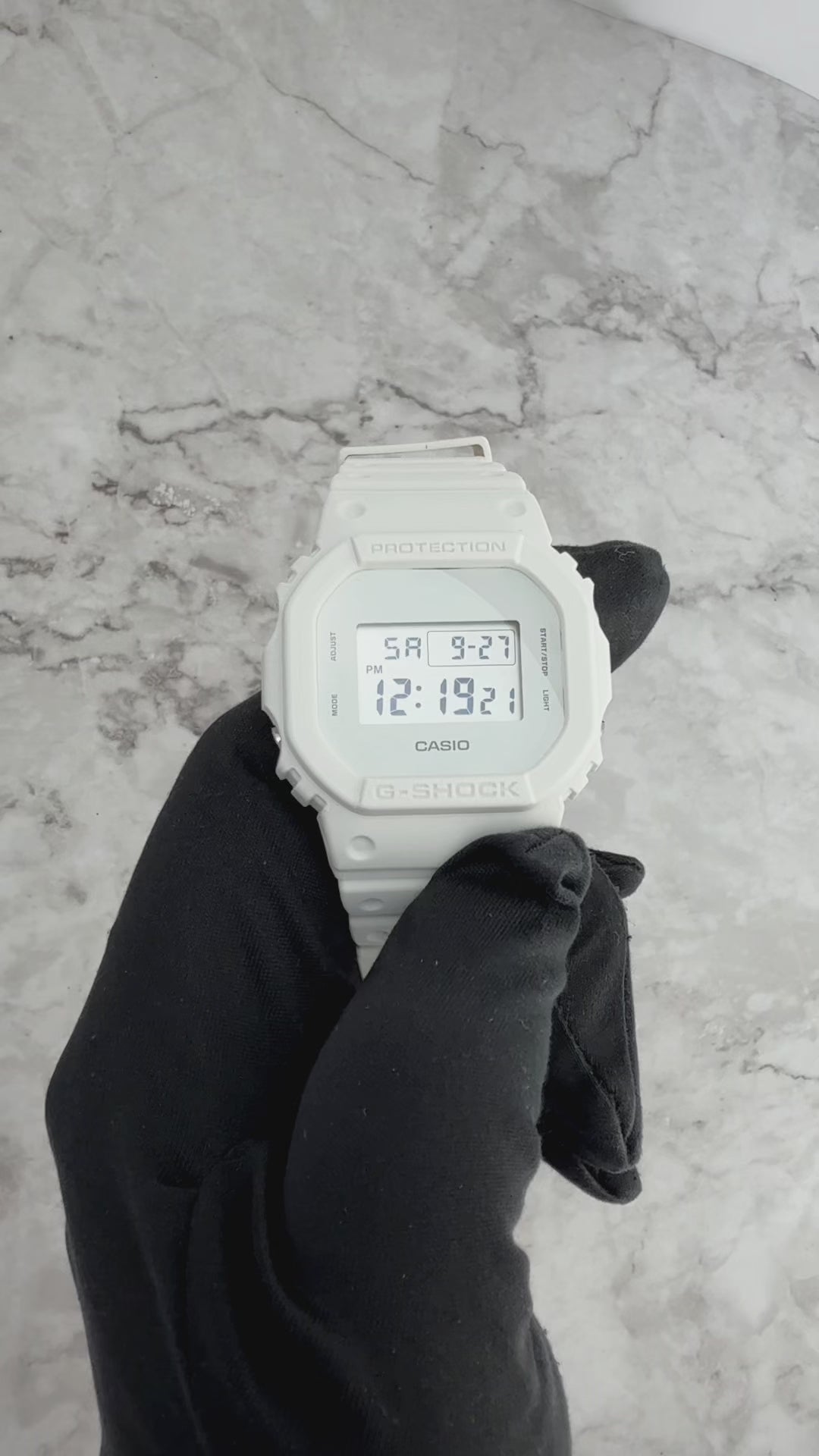 Casio G-SHOCK DW5600WW-7 all-white square model with resin case, bezel, band, and glass in monochrome design, featuring shock resistance, 200M water resistance, LED Super Illuminator backlight, stopwatch, and countdown timer.