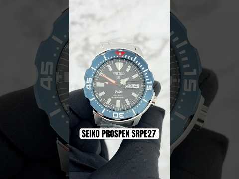 Seiko Prospex SRPE27 PADI Special Edition automatic diver watch with black dial, blue and red bezel, stainless steel case and bracelet, and magnified day-date display.